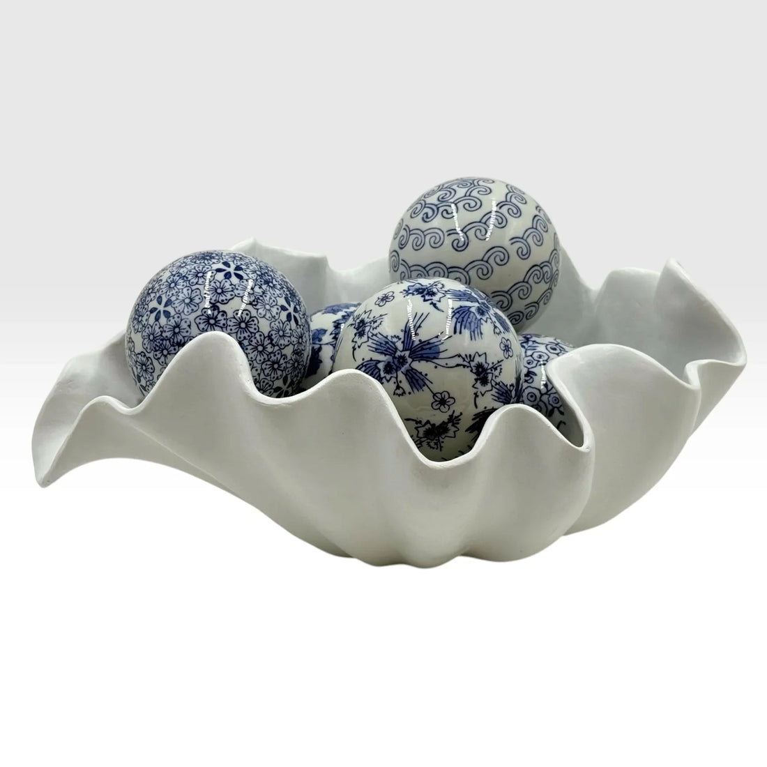 Blue and white porcelain decorative spheres in a scalloped ceramic bowl, elegant home décor accent