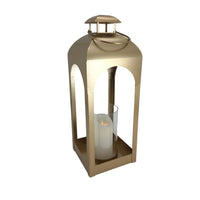 Gold metal lantern with arched cutouts holding a white candle, elegant home décor accent
