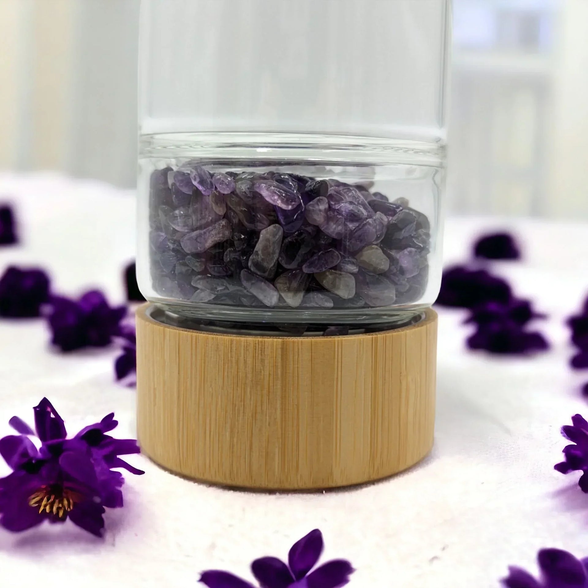 Amethyst crystal chips in glass jar with bamboo base, surrounded by purple flowers for home décor
