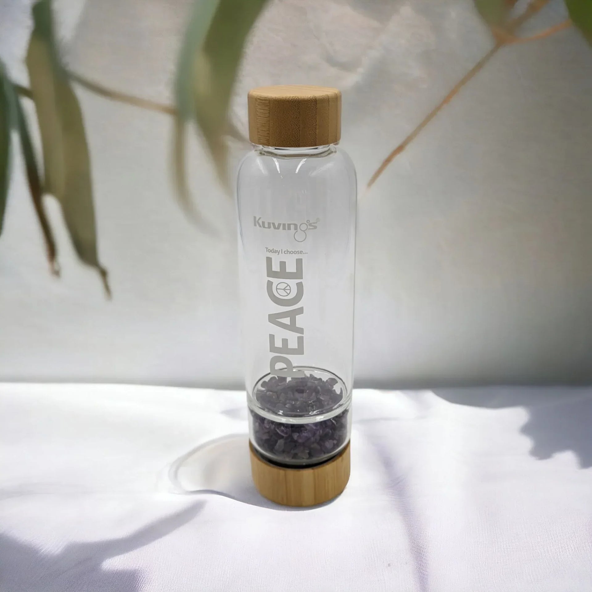 Glass water bottle with bamboo lid and amethyst stones, 'PEACE' etched, for mindful hydration and home décor