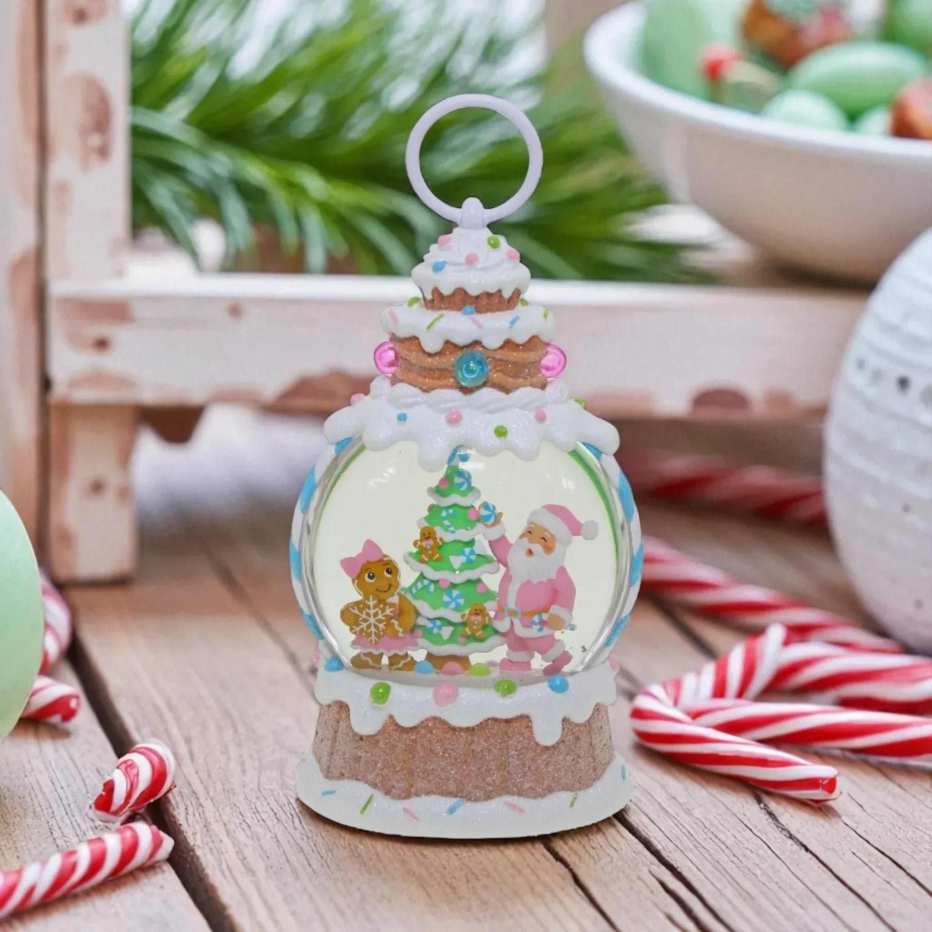 Festive snow globe with Santa, gingerbread, and Christmas tree, surrounded by candy canes