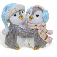 Charming penguin couple figurine in winter hats and scarves, perfect for home décor and holiday displays.