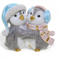 Charming penguin couple figurine in winter hats and scarves, perfect for home décor and holiday displays.