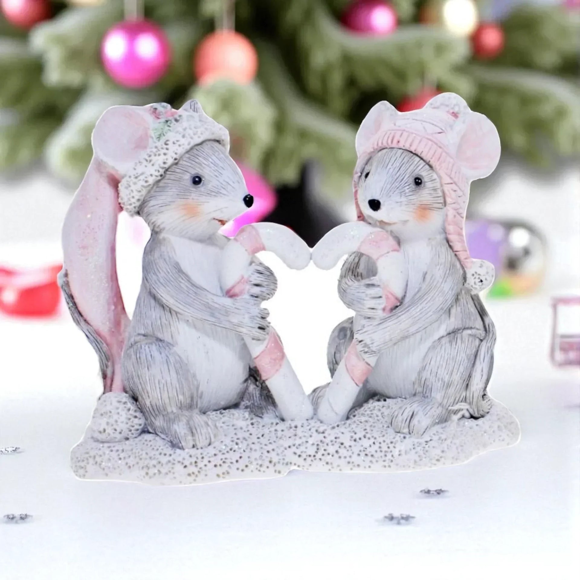 Charming mouse figurines in winter hats holding candy canes, festive holiday décor with Christmas tree background