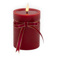 Red pillar candle with gold-trimmed ribbon bow, glowing flame for home décor ambiance