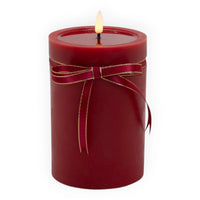 Red pillar candle with gold-trimmed ribbon bow, glowing flame for home décor ambiance