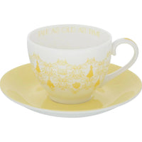 Elegant white teacup with gold 'Tale As Old As Time' script and ornate design, paired with yellow saucer