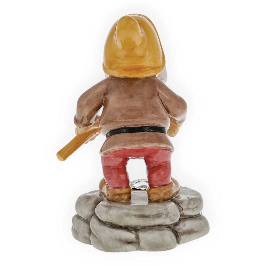Ceramic garden gnome figurine with yellow hat, red pants, holding tool, standing on stone base
