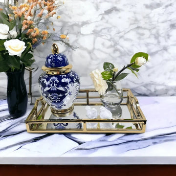 Blue and white porcelain ginger jar on a gold mirrored tray with white flowers