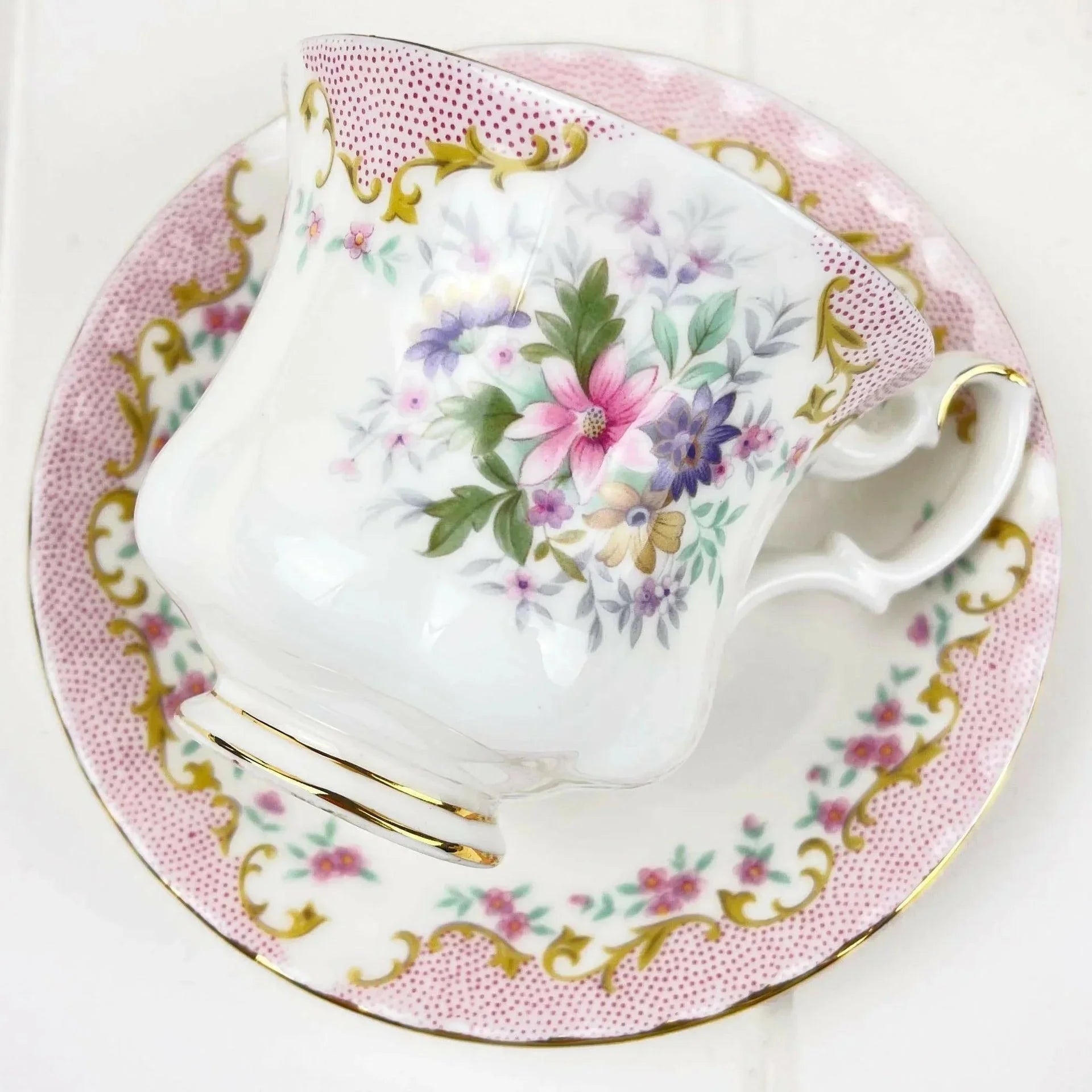 Elegant floral teacup and saucer set with pink polka dots and gold trim, perfect for home decor