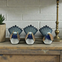 Three blue fairy wren figurines with fanned tails on rustic wood shelf, home décor accent