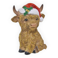 Cute Highland cow figurine wearing a festive Santa hat with holly, perfect for holiday home décor.