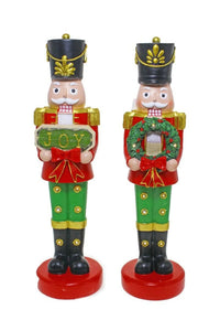 Two festive nutcracker figurines in red and green, one holding 'JOY' sign, other with wreath, holiday home décor